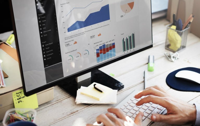 Pessoa trabalhando em frente ao computador, analisando gráficos e indicadores de desempenho em dashboard de dados, representando uso de People Analytics no RH.