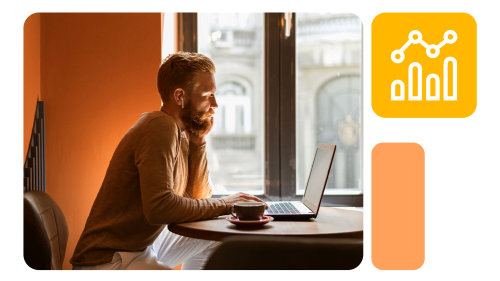 Homem ruivo sentado em mesa redonda usando notebook, com xícara à frente e ícone de análise de dados ao lado, em ambiente de iluminação suave.