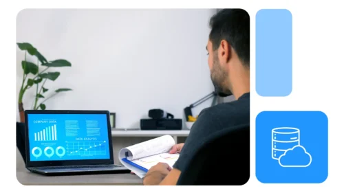 Homem analisando relatórios azuis em notebook sobre mesa clara, segurando planilhas impressas, ambiente de trabalho moderno.