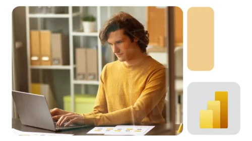 Pessoa de suéter amarelo trabalhando concentrada em um notebook em escritório moderno, com gráficos na mesa e ícone do Power BI ao lado.