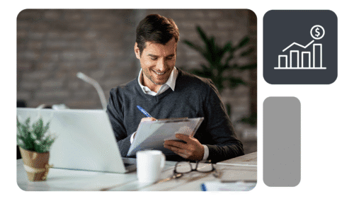 Homem senta à mesa com notebook, segurando prancheta e caneta; ícone de gráfico financeiro ao lado.
